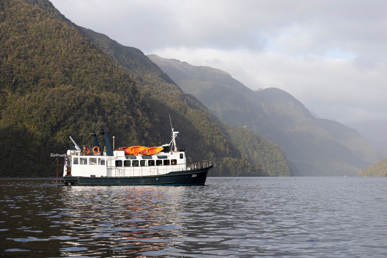 MV Tutoko at anchor under the fiord walls in soft light