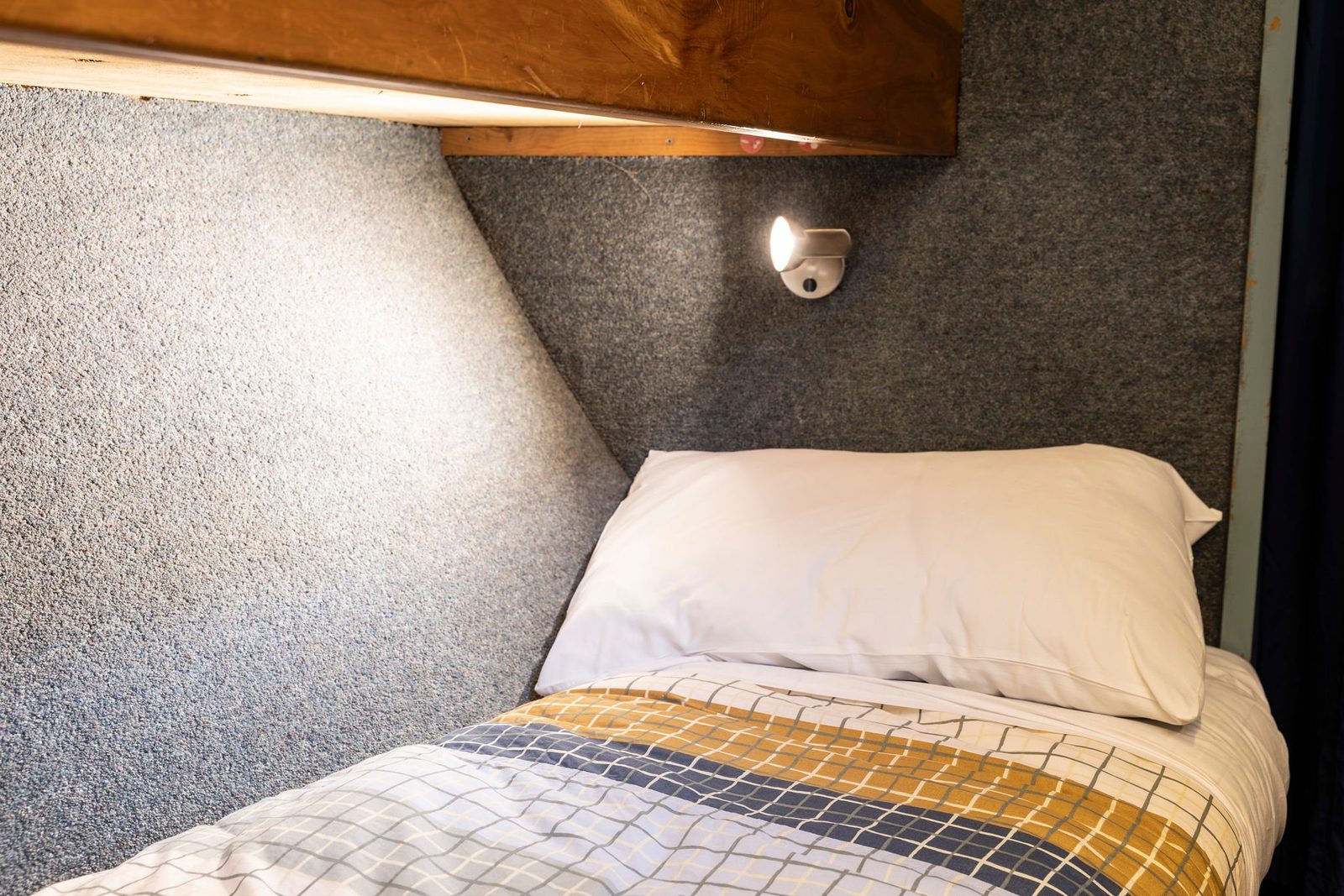 A made-up bunk berth with its own reading light aboard MV Tutoko