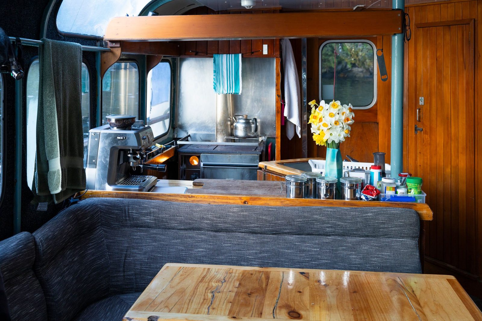 The saloon and galley aboard MV Tutoko with a wooden table and fresh daffodils