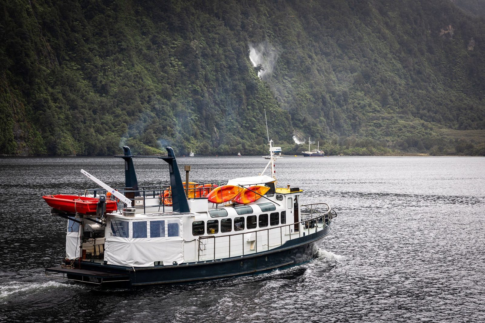 MV Tutoko underway in Doubtful Sound with the tender on the davit and kayaks on the roof