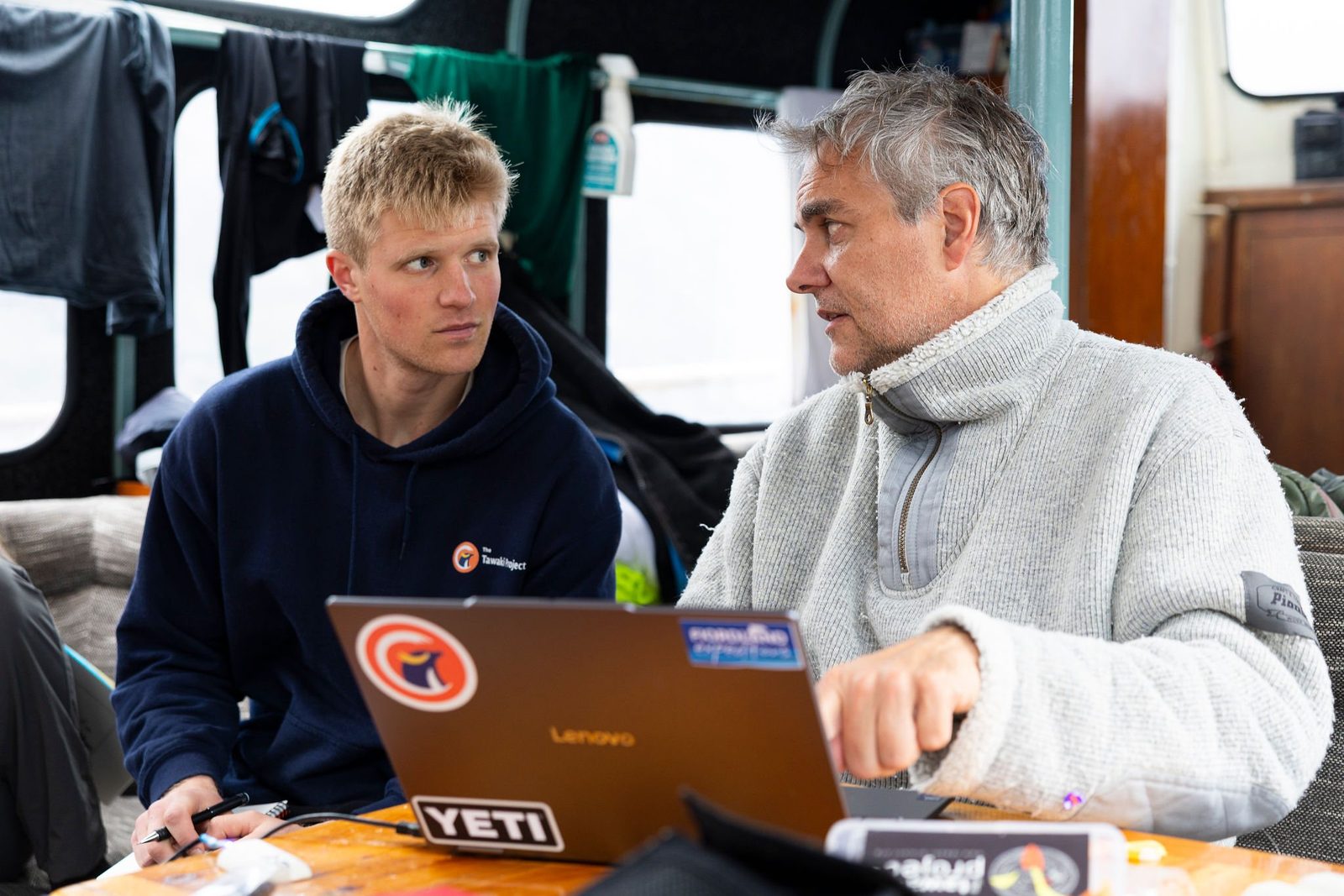 Tawaki Project researchers planning the nest survey with a laptop in the saloon of MV Tutoko